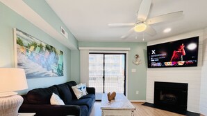 Ein Wohnzimmer mit einer Couch, einem Couchtisch, einem an der Wand befestigten Fernseher und einem Kamin.