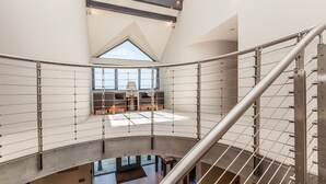 A spacious atrium with a high ceiling, a mezzanine level with seating, and a staircase with metal railings.