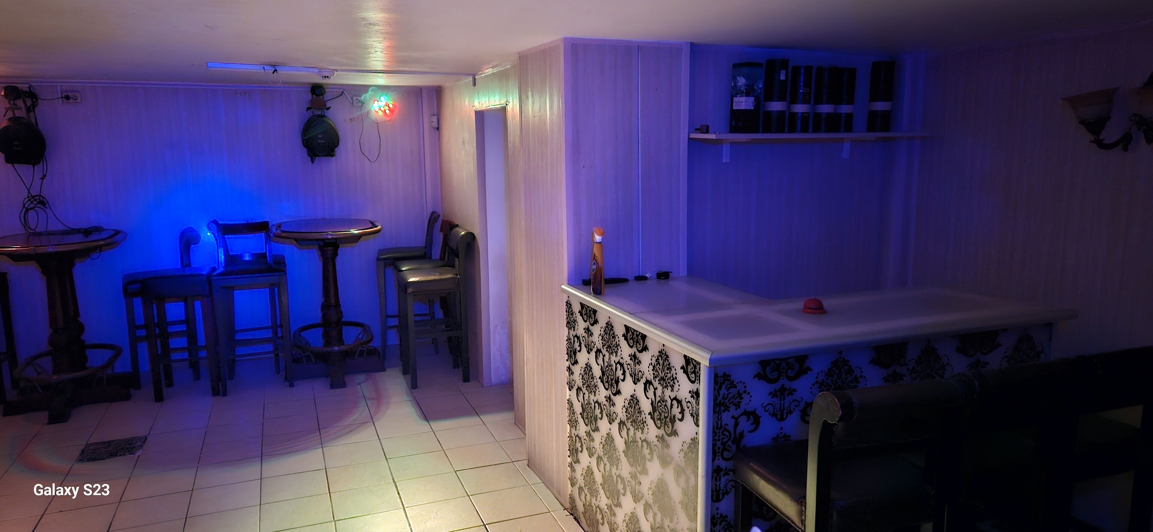 A room with a bar area, a dining table with chairs, and a patterned wall.