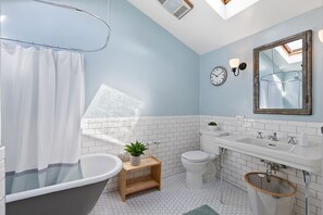 Une salle de bain moderne avec une baignoire sur pieds, des toilettes, un lavabo et un miroir.