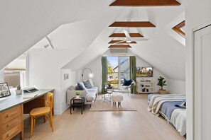 Une chambre confortable située dans les combles, avec un bureau, une chaise, un canapé et un lit.