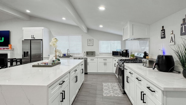 A modern kitchen with white cabinetry, a large island, and a central island with a built-in oven.