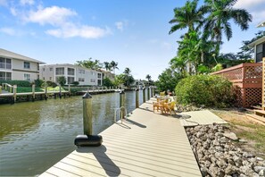 A wooden dock extending into a calm waterway, surrounded by lush greenery and residential buildings.