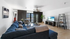 Un soggiorno moderno con un divano blu, un tavolino da caffè, una TV e una libreria.