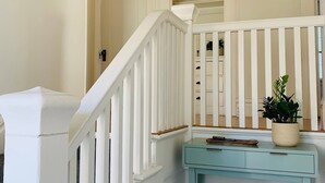Un escalier avec des rampes blanches et une console bleu clair sur laquelle est posée une plante en pot.