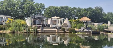 A tranquil outdoor area with a pond, a gazebo, and a thatched-roof structure.