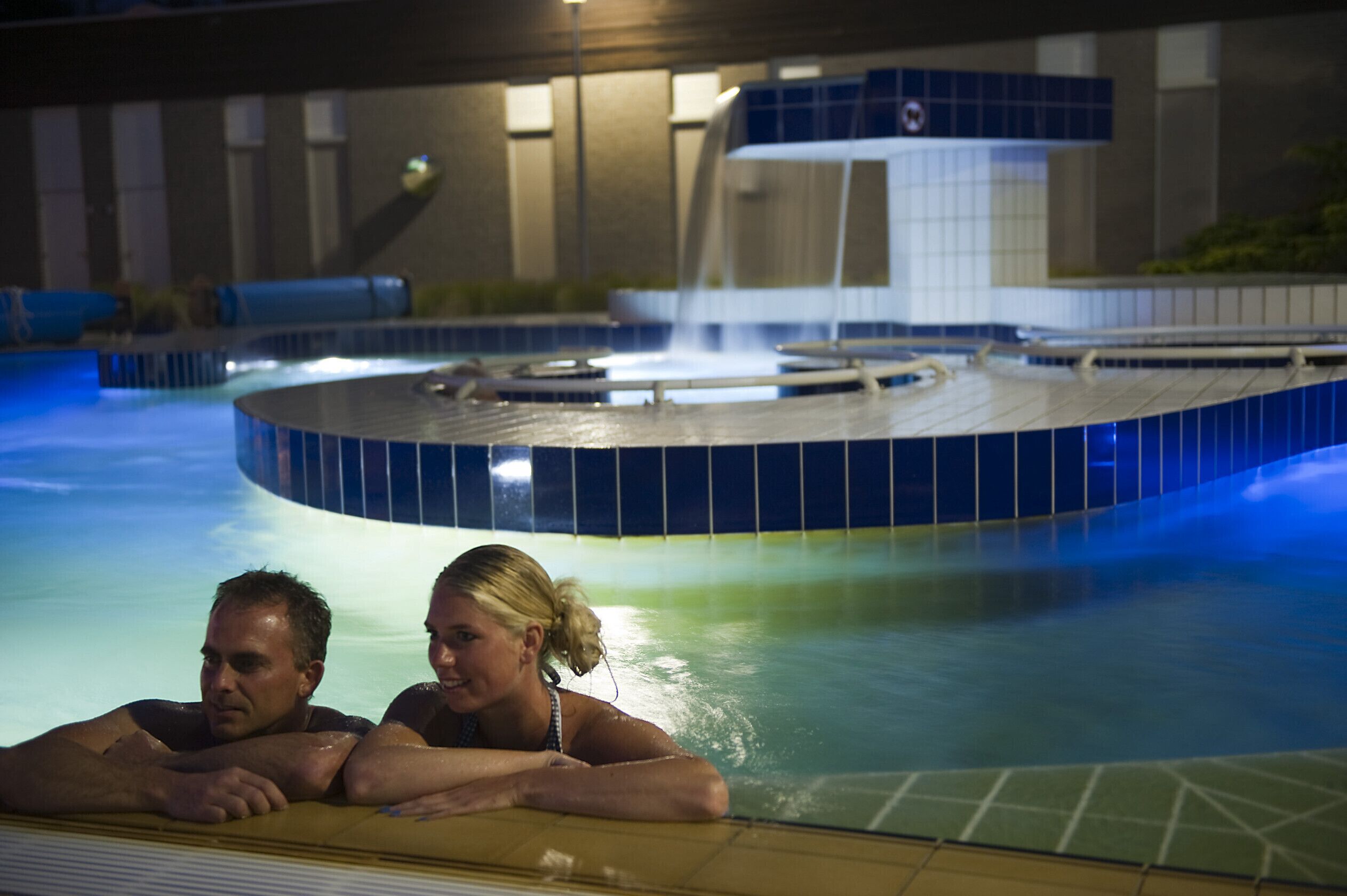En swimmingpool med et cirkulært spabad og et vandfald.