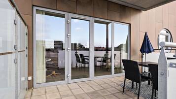 A balcony with a glass door, a table, chairs, and an umbrella.