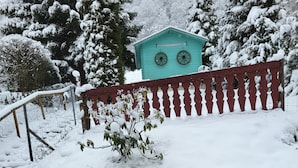 Un jardin enneigé, avec une clôture en bois et un petit abri bleu.