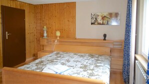 Une chambre à coucher aux murs lambrissés, avec un lit, une table de chevet, une lampe et un tableau accroché au mur.