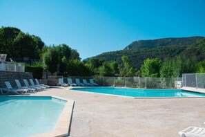 A pool area with multiple lounge chairs and a clear view of a mountainous landscape.