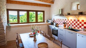 A kitchen with a view of the countryside, a dining table with chairs, and a window with a view. - Gîte Aulas 2/4 Pers - LA Tieule (LA TIEULE)