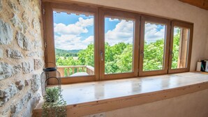 A room with a large window overlooking a green landscape. - Gîte Aulas 2/4 Pers - LA Tieule (LA TIEULE)