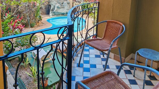 A balcony with a view of a pool and palm trees.