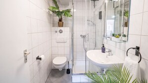 Une salle de bain moderne équipée de toilettes, d’un lavabo et d’une douche.