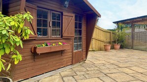 A wooden building with large windows, a wooden door, and a window box with flowers. - 1 bedroom accommodation in Camerton, near Bath (Camerton, near Bath)
