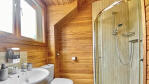 A wooden-paneled bathroom with a sink, toilet, and glass-enclosed shower. - 1 bedroom accommodation in Camerton, near Bath (Camerton, near Bath)