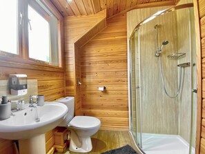 Een badkamer met houten lambrisering, een wastafel, toilet en douchecabine met glazen wanden.