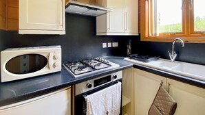 A compact kitchen with a microwave, stove, oven, and sink. - 1 bedroom accommodation in Camerton, near Bath (Camerton, near Bath)