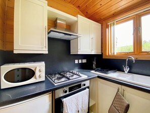 Een kleine keuken met een magnetron, fornuis, oven en spoelbak.