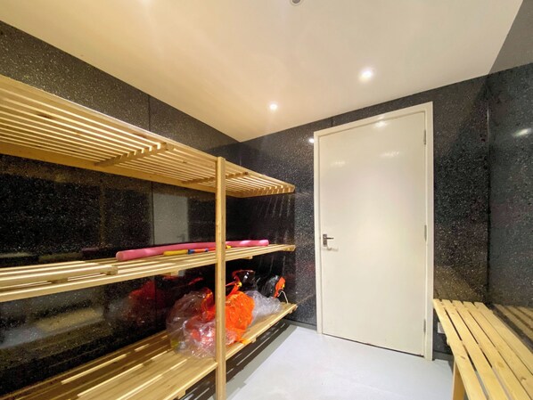 Une pièce avec un lit superposé, une porte blanche et un banc.