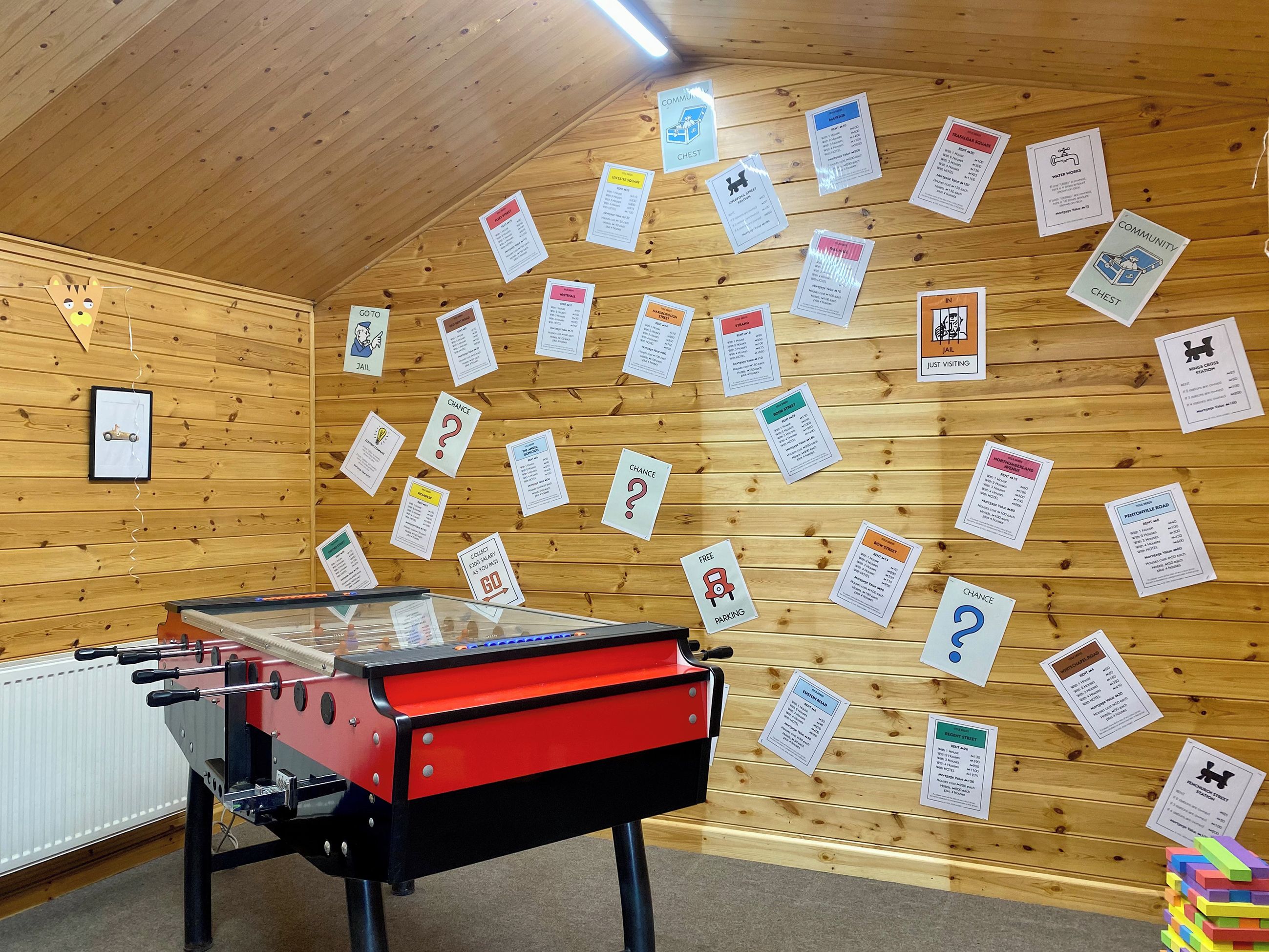 A room with a foosball table, wooden walls, and various informational signs.