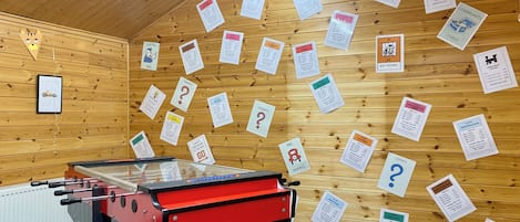 A room with a foosball table, wooden walls, and various informational signs.