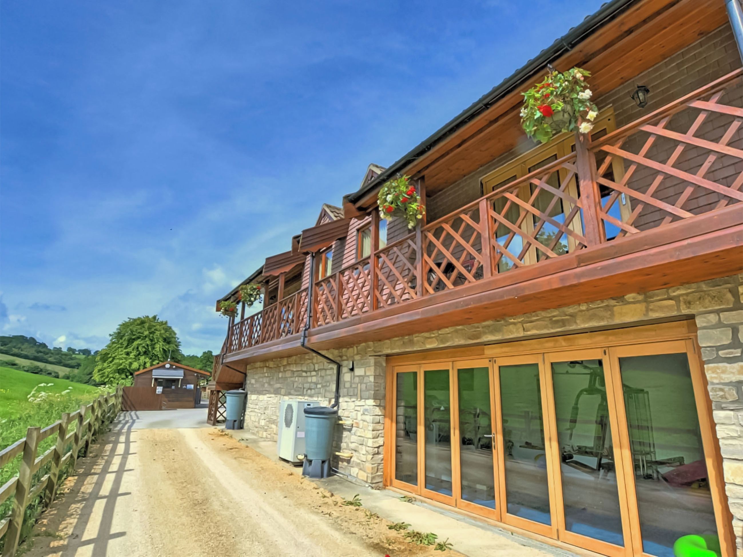 A two-story building with a stone facade, wooden balcony railings, and large glass doors.