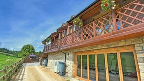 A two-story building with a stone facade, wooden balcony railings, and large glass doors. - 1 bedroom accommodation in Camerton, near Bath (Camerton, near Bath)