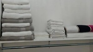 Uno spazio contenitivo con scaffali pieni di asciugamani piegati e un appendiabiti.