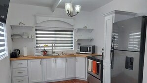 Una cucina moderna con mobili bianchi, un frigorifero in acciaio inossidabile, un forno a microonde e un lavandino.