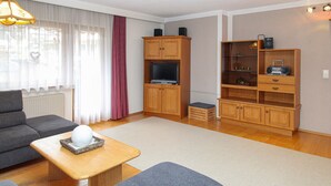 A living room with a sofa, a coffee table, a TV stand, and a cabinet with a radio. - Apartment mit Bergblick (Aschau im Zillertal)