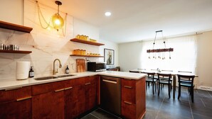A modern kitchen with marble countertops, wooden cabinets, a built-in dishwasher, and a dining area with a table and chairs. - Near KYSHP & Fasig-Tipton
Equestrian & Bourbon Tours Central
The Kingston!! (Lexington)