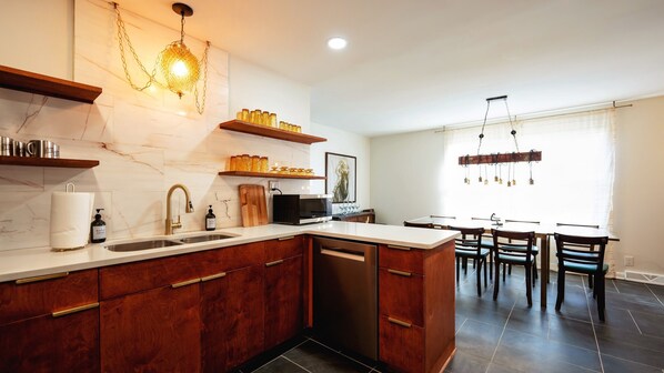 Una cucina moderna con piani in marmo, mobili in legno, lavastoviglie integrata e una zona pranzo con tavolo e sedie.