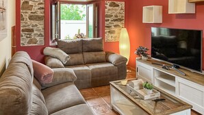 En stue med sofa, fjernsyn og en stenvæg.