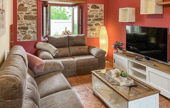 A living room with a sofa, a TV, and a stone wall. - Cozy apartment in O Porto de Espasante (O Porto de Espasante)