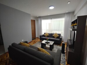 Una sala de estar moderna con un conjunto de sofá, una mesa de centro y un televisor.