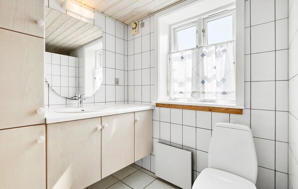 A modern bathroom with a white sink, mirror, and toilet.