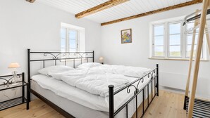 A bedroom with a bed, a bedside table, a lamp, and a window. - Nice home in Grenaa with sauna (Grenaa)