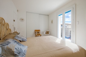Una camera da letto con un letto, una sedia, un tavolino e una porta che dà su un balcone.