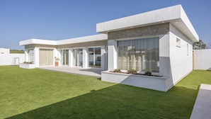 Ein modernes Haus mit Flachdach, großen Fenstern und einem gepflegten Rasen.