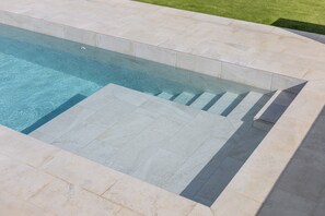 Une piscine à l’eau claire, entourée de carreaux de couleur claire.