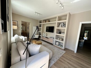 A modern living room with a sofa, TV, and built-in shelves. - Villa 'Romantica Lake Idro' with Private Pool, Wi-Fi and Air Conditioning (Bagolino)