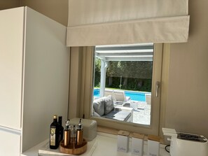 A room with a window overlooking a pool, a coffee station, and a toaster. - Villa 'Romantica Lake Idro' with Private Pool, Wi-Fi and Air Conditioning (Bagolino)