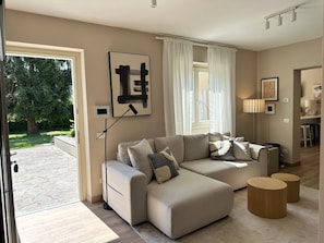 A modern living room with a sectional sofa, a floor lamp, and a view of the outdoors. - Villa 'Romantica Lake Idro' with Private Pool, Wi-Fi and Air Conditioning (Bagolino)