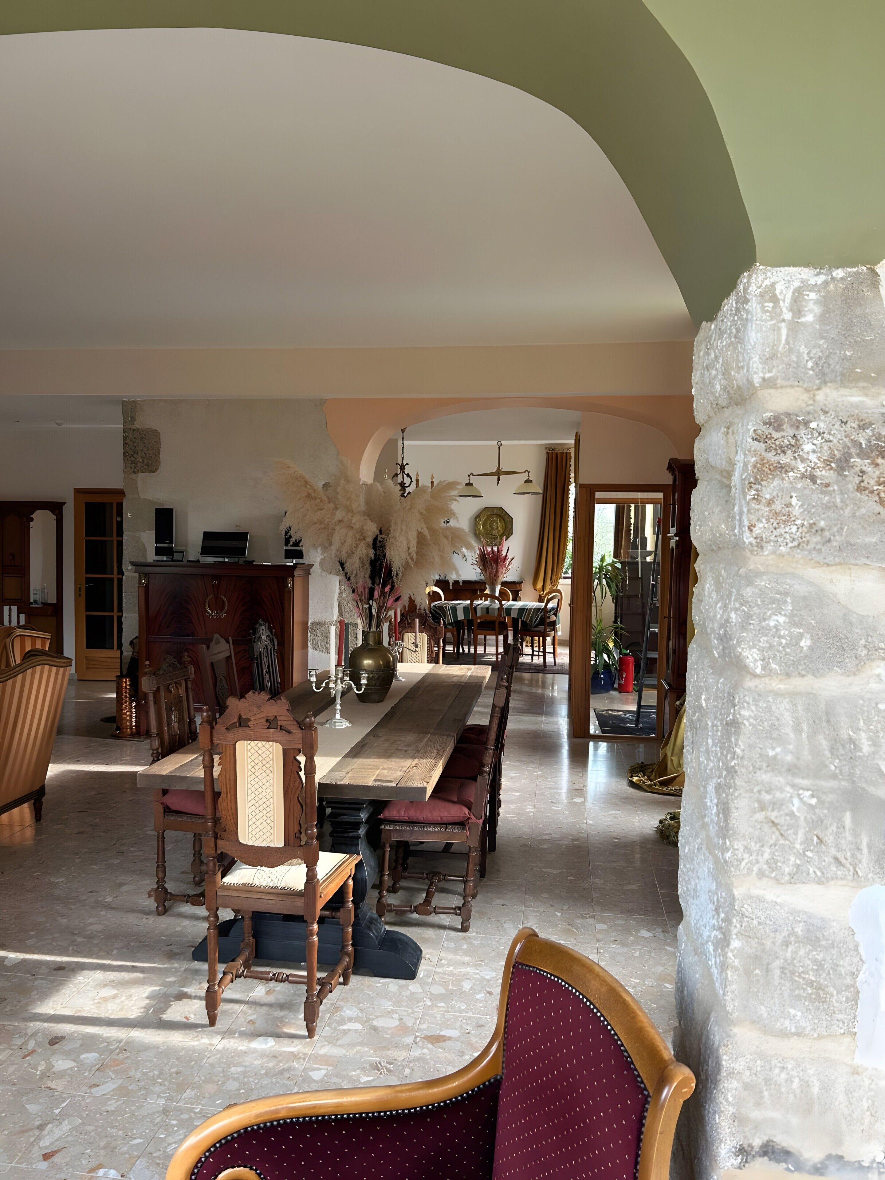 A dining area with a long wooden table, chairs, and a chandelier.