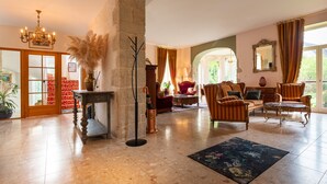 A spacious living room with a stone pillar, a chandelier, and a large window with curtains. - Castle 'Gite La Renardière' with Private Pool, Private Terrace and Wi-Fi (Langoëlan)