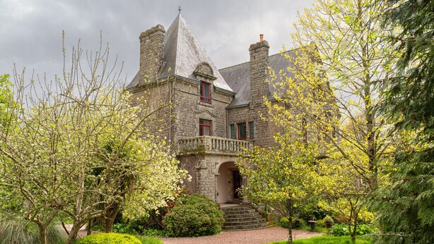 A historic stone building with a prominent tower, a central entrance, and a well-maintained garden. - Castle 'Gite La Renardière' with Private Pool, Private Terrace and Wi-Fi (Langoëlan)