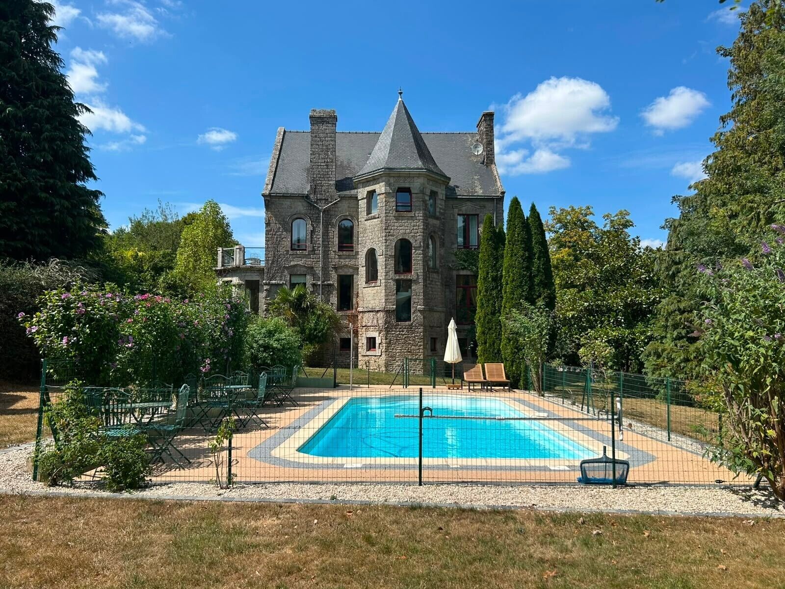 A large stone building with a swimming pool in front.