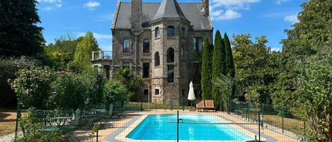 A large stone building with a swimming pool in front.